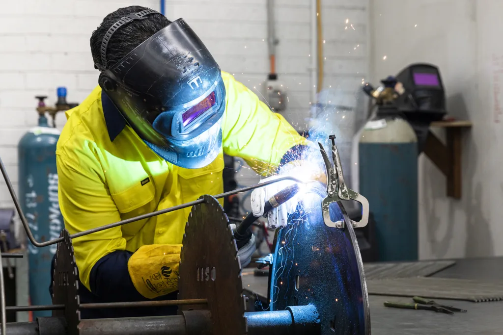 A man welding a table with a mig welder.