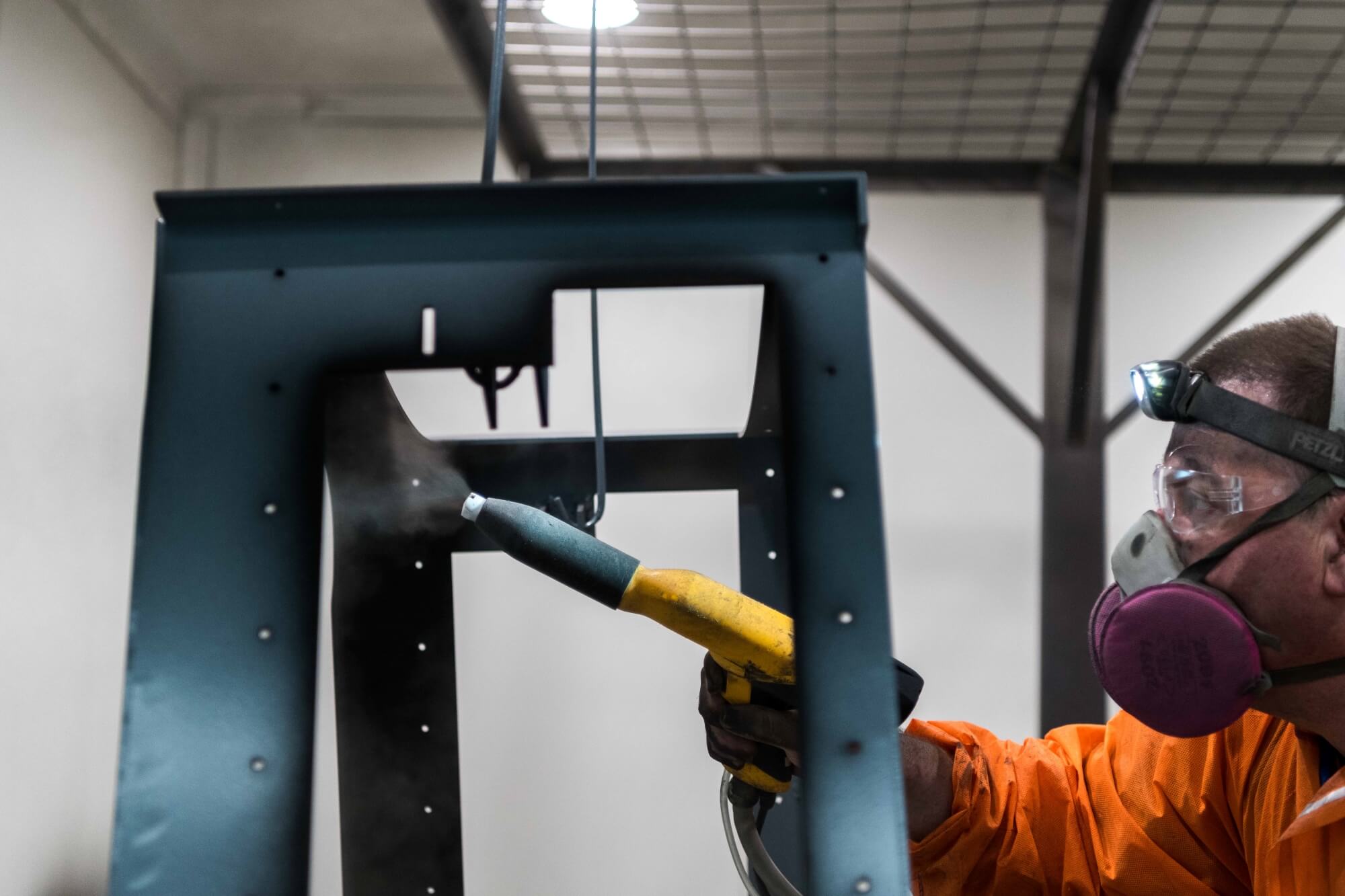 A man powdercoating a custom designed frame for an outdoor bar.